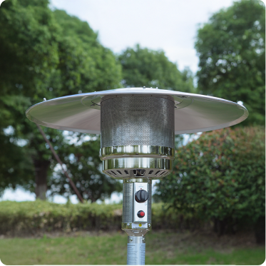 A silver outdoor heater with a domed top with trees and shrubs in the background.