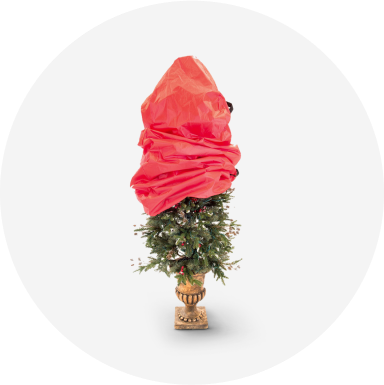 A red Christmas tree storage bag partially covering an artificial tree in a gold stand.