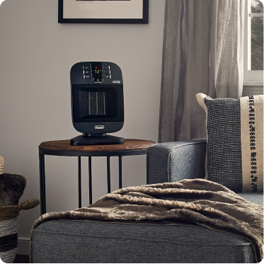 Small black heater with orange top and silver safety grate with a blurry campsite in the background.