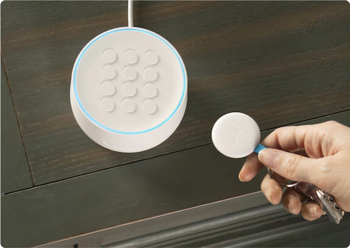 A person's hand next to a smart home hub.